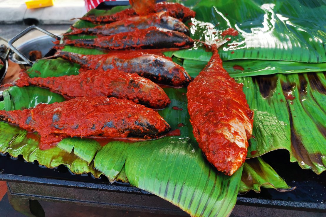 A close-up shot of fishes being grilled on a charcoal grill